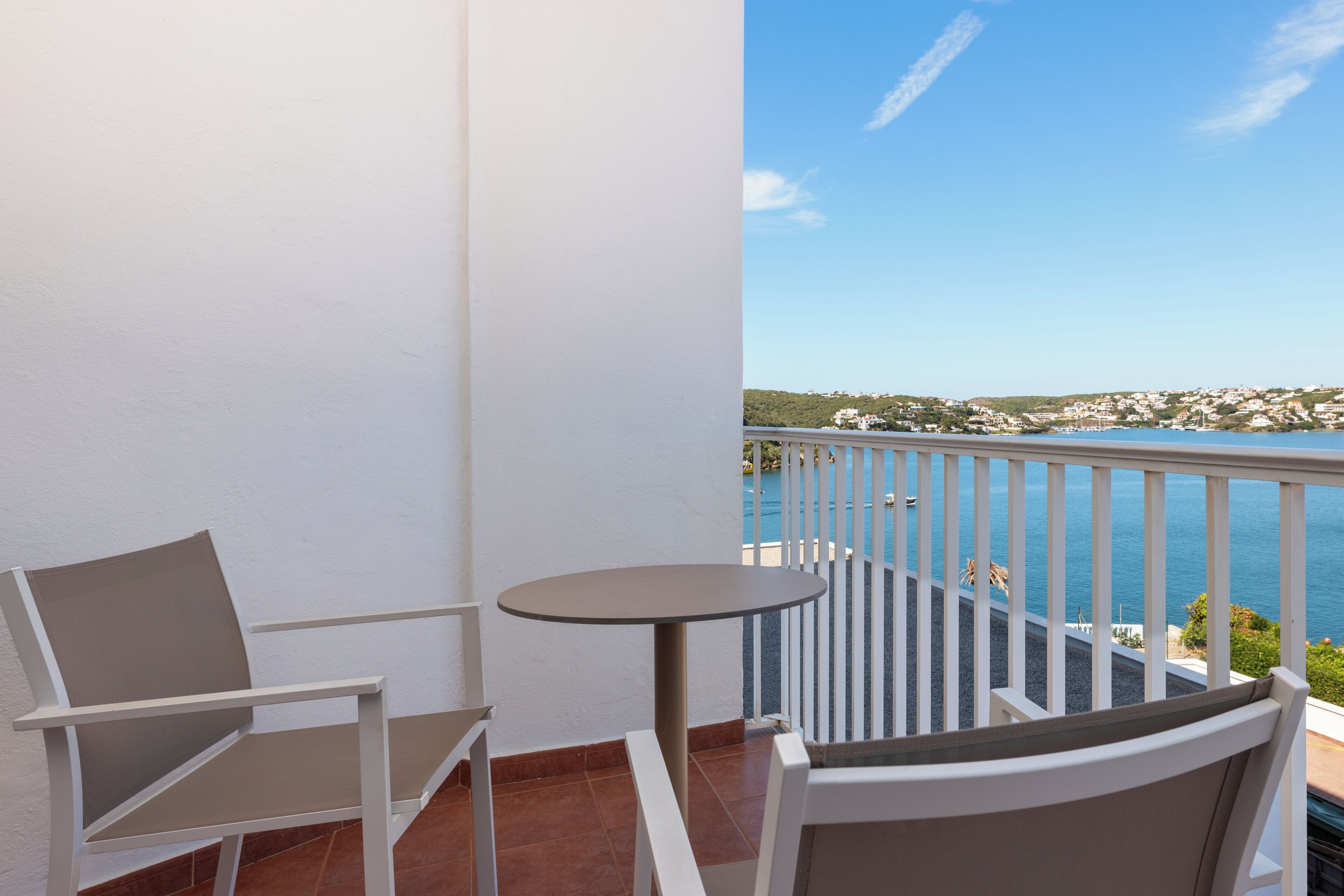 A balcony with a white railing, a round table, and two chairs.