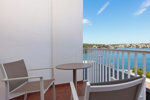 A balcony with a white railing, a round table, and two chairs.