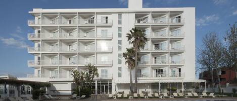 Un hôtel à plusieurs étages doté de balcons, d’une piscine et de chaises longues.