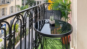 A balcony with a black table, potted plants, and a yellow hotel banner. - Hotel Nap By HappyCulture (Nice)
