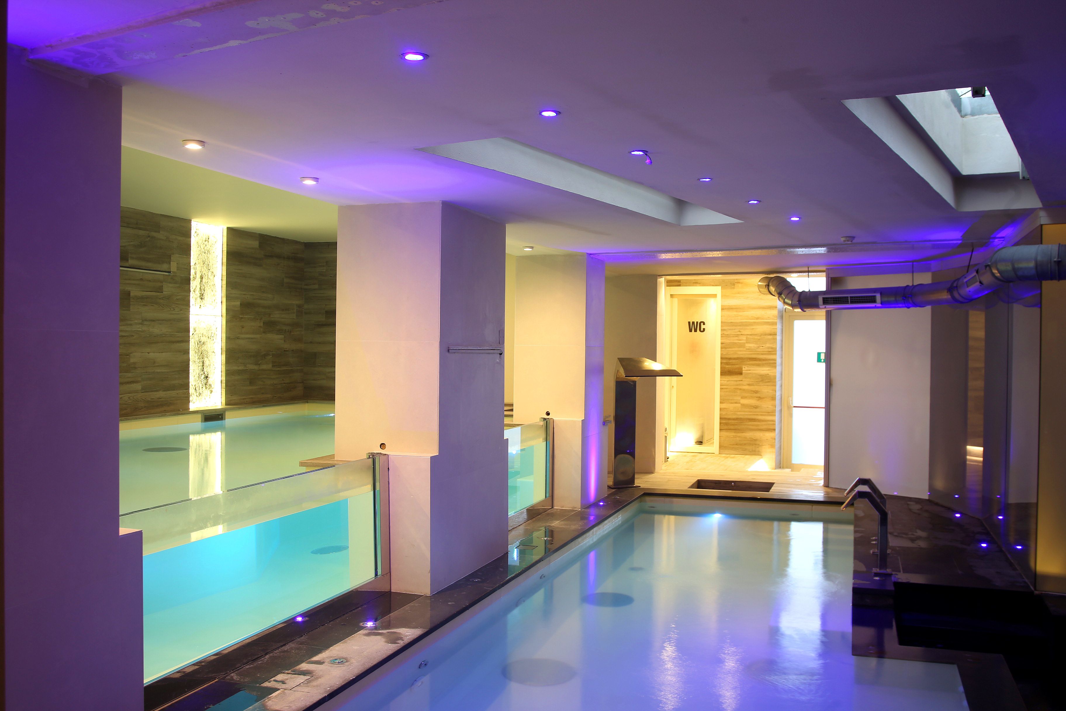 A modern indoor swimming pool with glass barriers and a clear water surface.