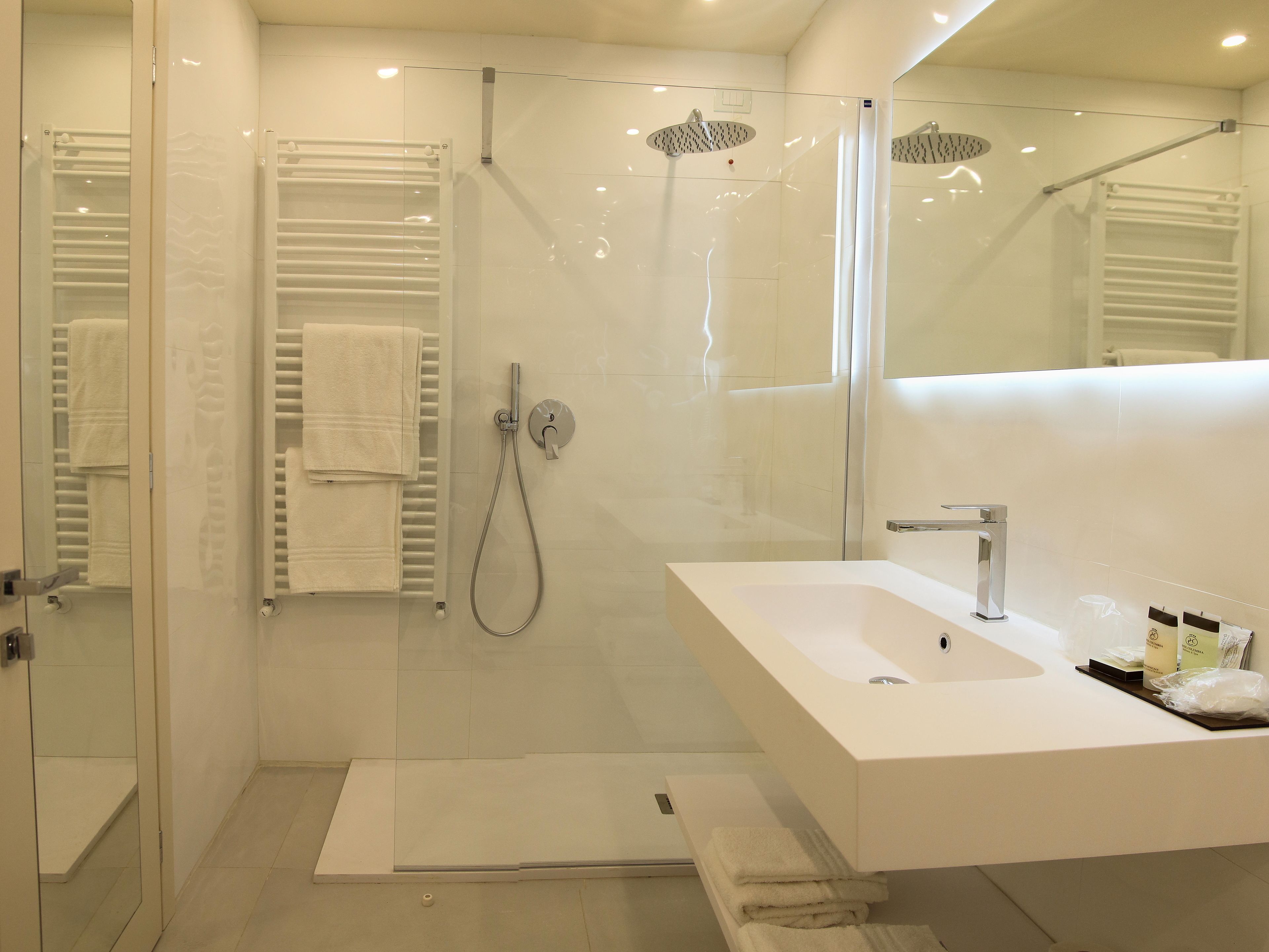 A modern bathroom with a glass-enclosed shower, a white sink, and a large mirror.