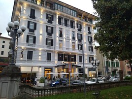 Un hotel de varios pisos con arquitectura clásica europea, con balcones y una entrada central con un cartel.