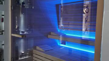 Een moderne badkamer met een glazen douchecabine, blauwe LED-verlichting en een houten wastafelmeubel.