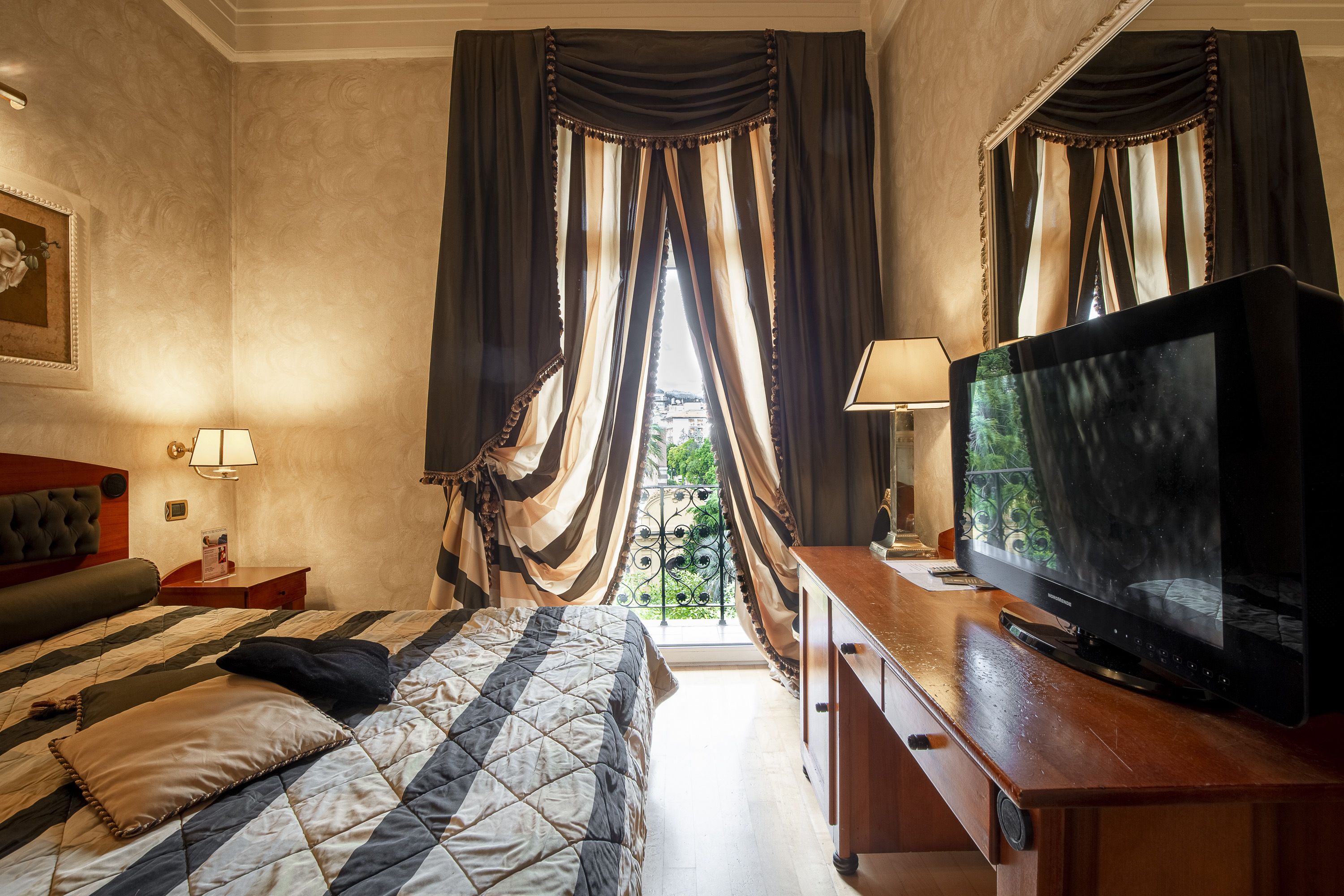 A hotel room with a bed, a television, and a view of the outdoors.