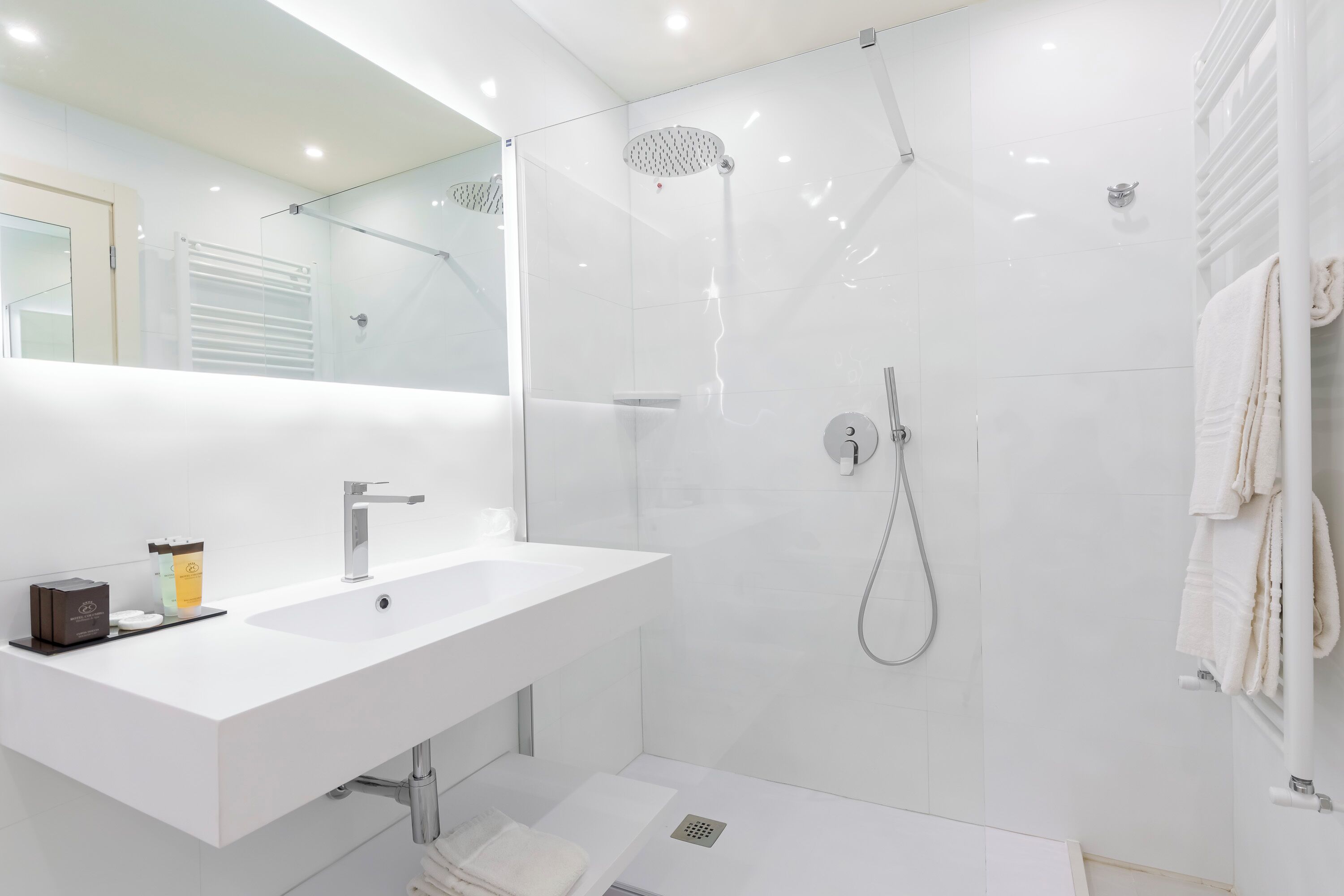 A modern bathroom with a white sink, mirror, and shower.