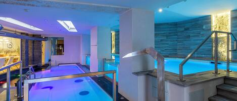 Una piscina interior moderna con una escalera de madera y un tragaluz.