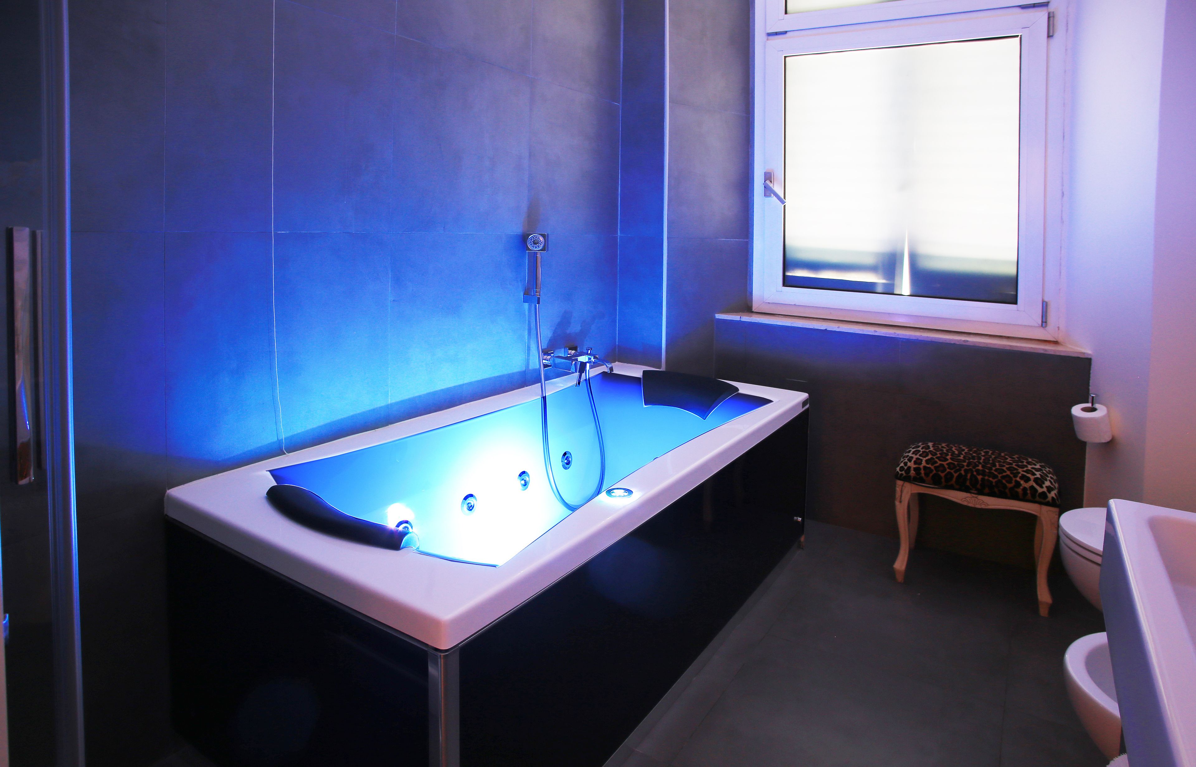 Ein modernes Badezimmer mit einer freistehenden Badewanne, einem kleinen Holzschemel und einer Toilette.