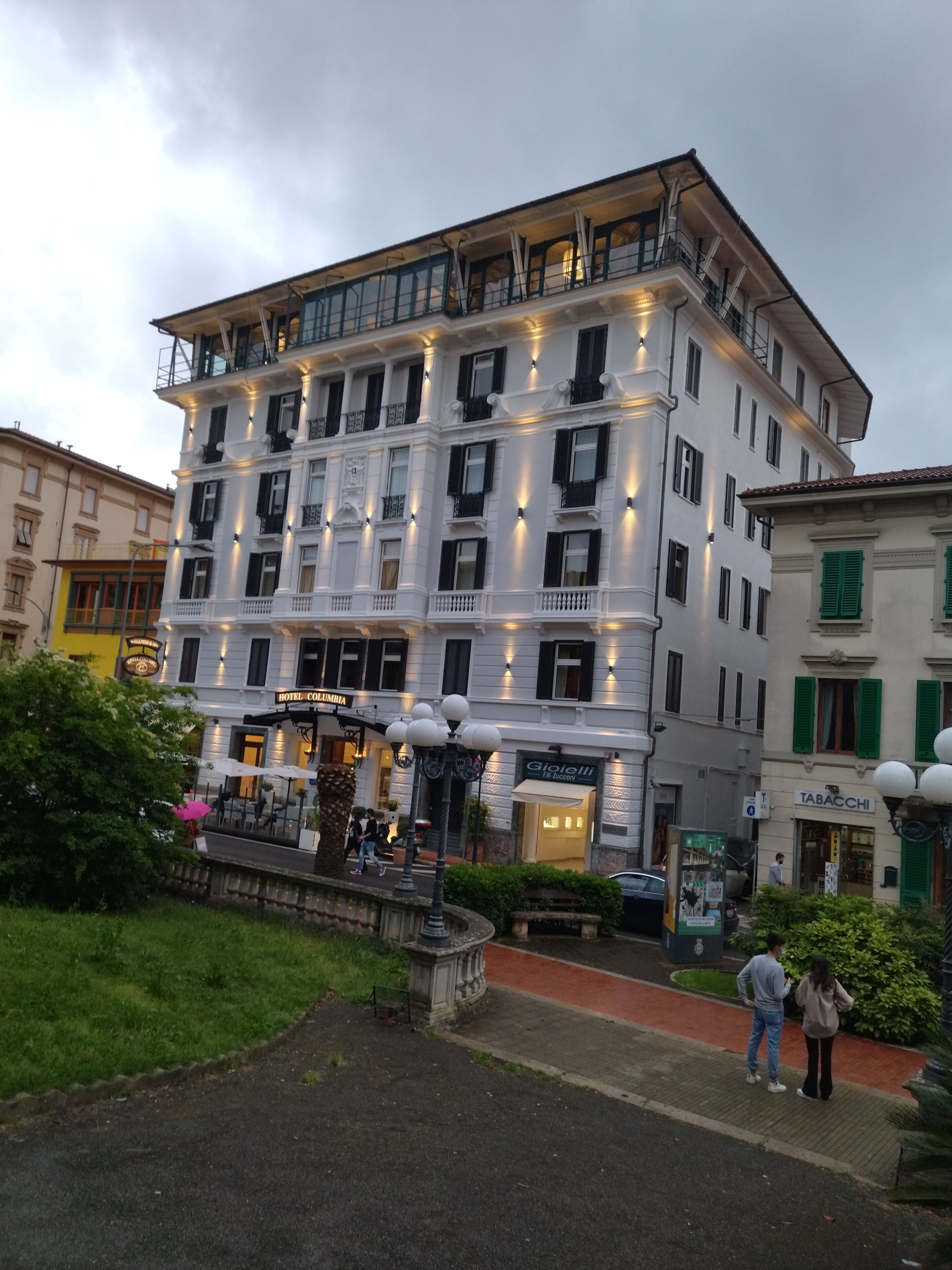 Ein mehrstöckiges Hotel mit einem Balkon im oberen Geschoss, einem Restaurant im Erdgeschoss und einem Springbrunnen im Innenhof.