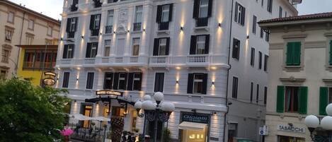 Ein mehrstöckiges Hotel mit einem Balkon im oberen Geschoss, einem Restaurant im Erdgeschoss und einem Springbrunnen im Innenhof.