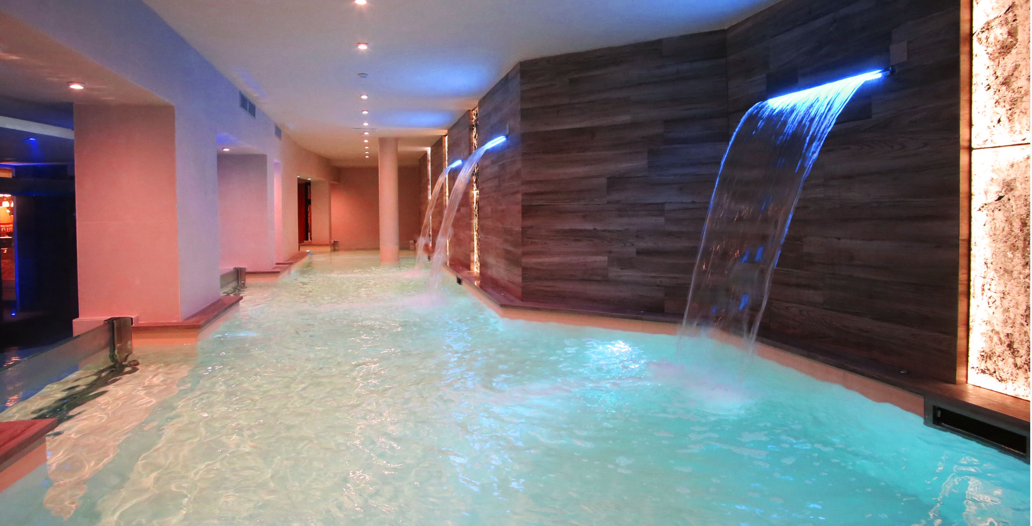 Un área de spa con una piscina larga y estrecha y una cascada.