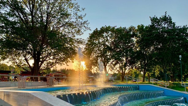 Un parc public doté d’une fontaine, d’une piscine et d’un escalier menant à l’eau.
