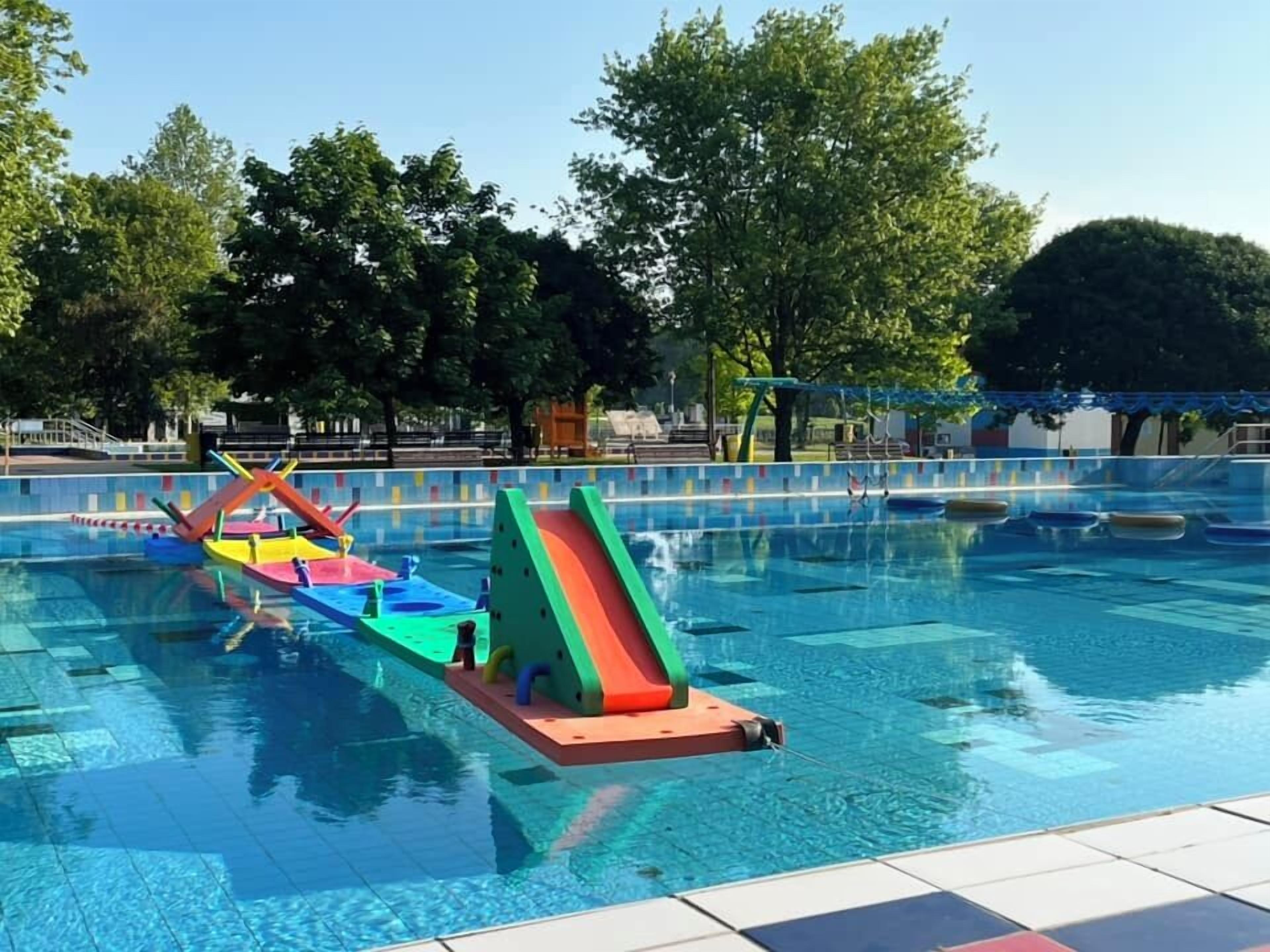 A swimming pool with colorful play structures and a slide.