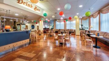A spacious bar area with a counter and seating, decorated with colorful paper lanterns.