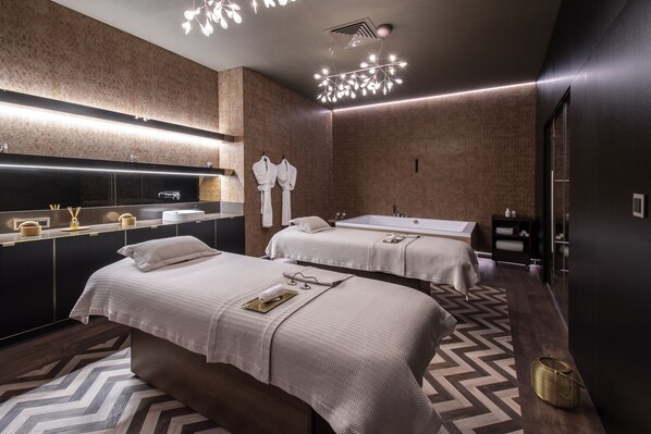 A modern hotel room with two beds, a large mirror, a vanity with a sink, and a chandelier. - EPIC SANA Marques Hotel (Lisbon)