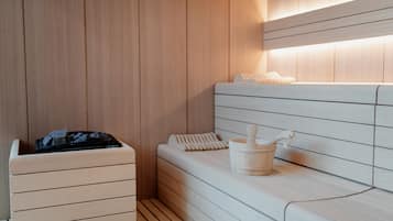 Una sauna moderna con paneles de madera, un banco y un balde.