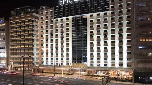 Un hotel moderno con un llamativo letrero que dice "EPIC SANA", que presenta una fachada tipo entramado y varios pisos.