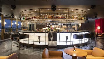 A bar area with a circular bar, multiple seating options, and a city view.
