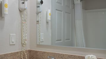 Baño con lavamanos, espejo, secador de pelo y dispensador de toallas.