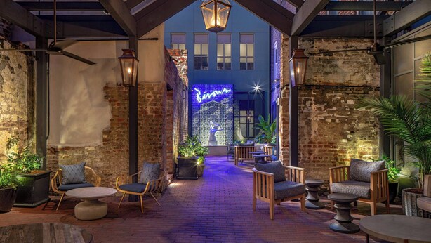 An outdoor patio with brick flooring, wooden furniture, and potted plants. - The Eliza Jane, Autograph Collection (New Orleans)