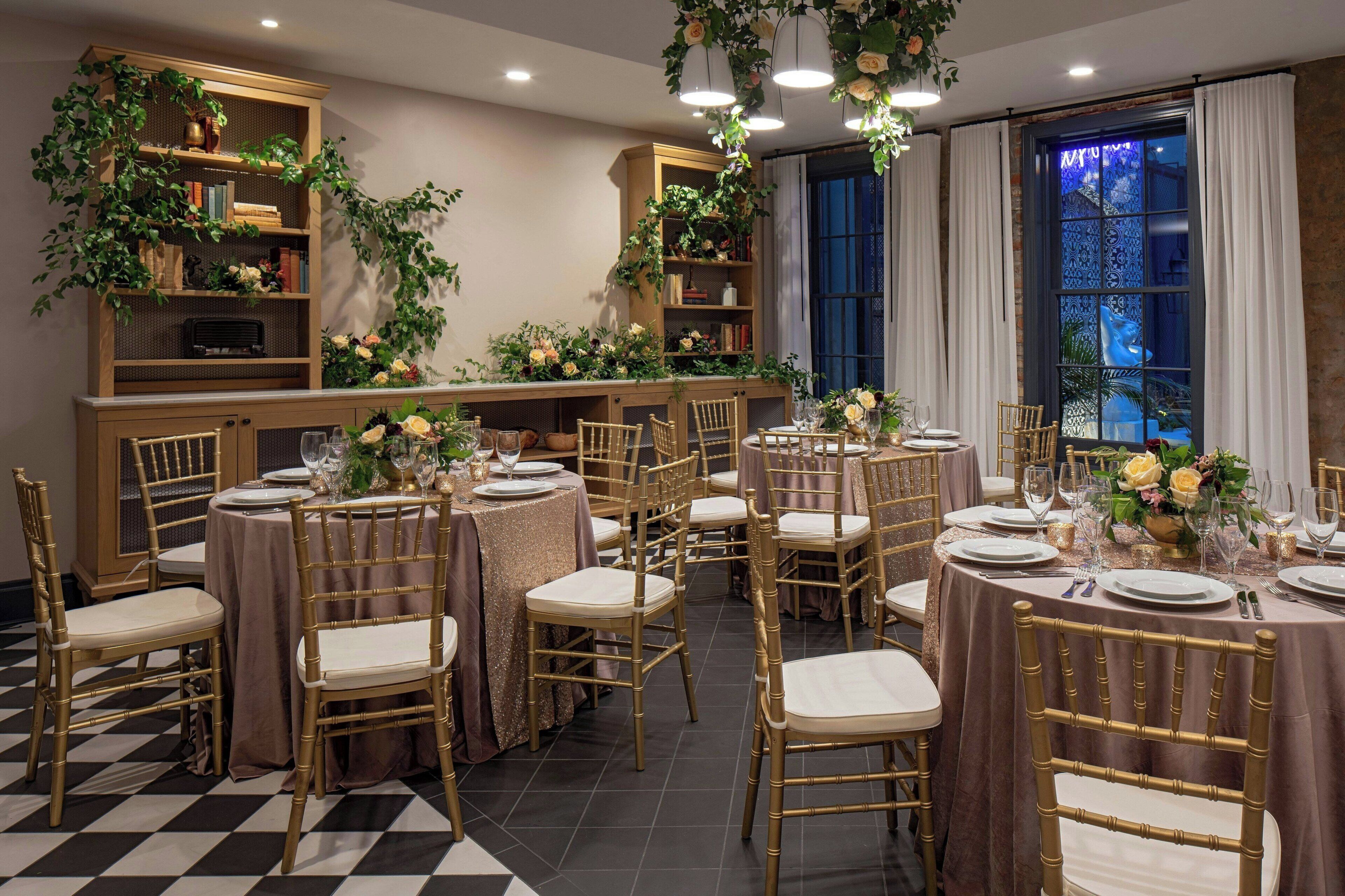 A dining area with round tables, gold chairs, and floral centerpieces.