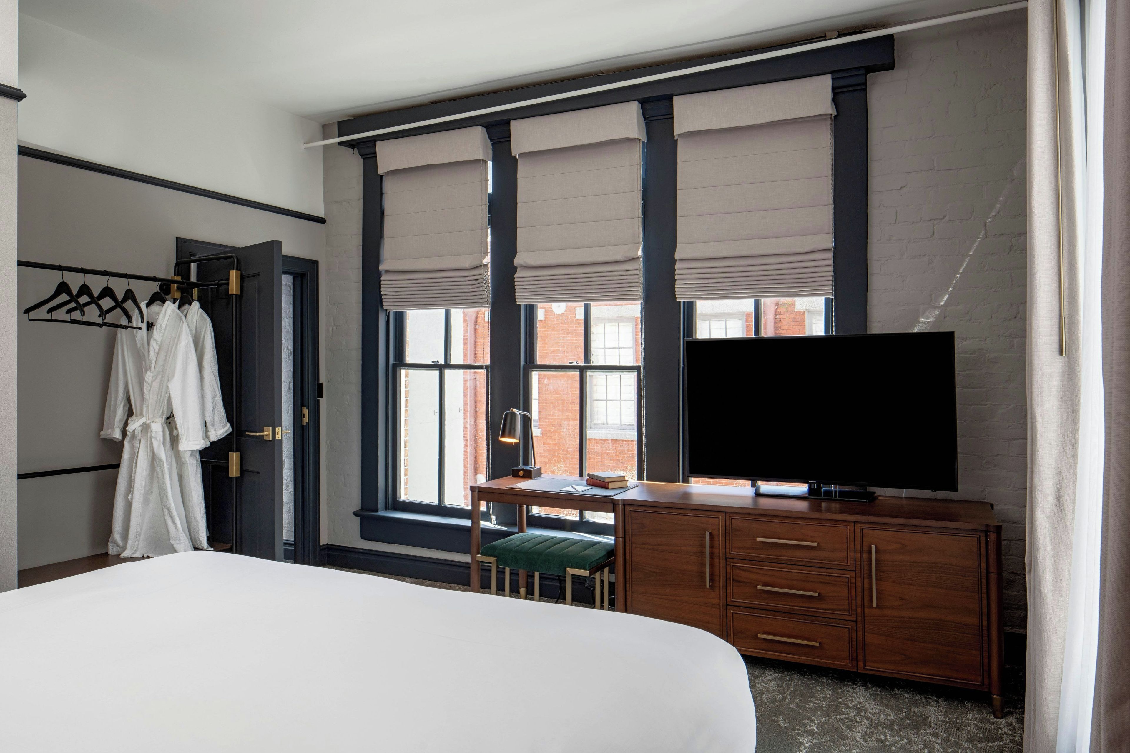 Une chambre d’hôtel comprenant un lit, un bureau avec une chaise, une télévision et une armoire.