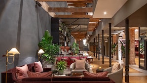A modern interior with a sofa, armchairs, and a dining area. - The Eliza Jane, Autograph Collection (New Orleans)