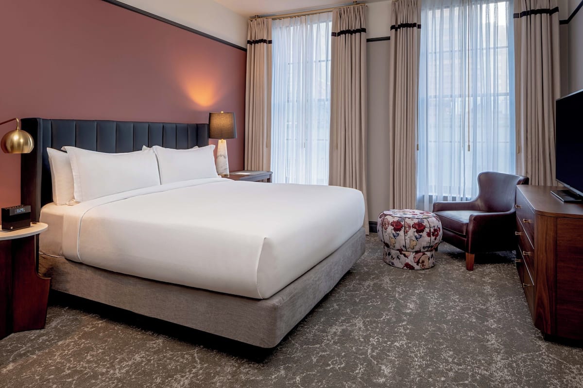 Una habitación de hotel con una cama, un escritorio, una silla, un televisor y una lámpara.