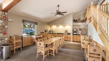 A wooden interior with a kitchen area, dining tables, and a staircase.