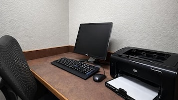 Een computerbureau met een monitor, toetsenbord, muis en een HP printer.