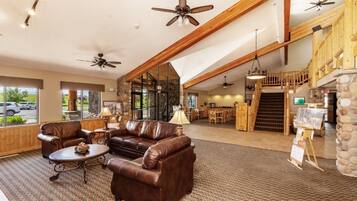 A spacious lobby with leather sofas, a coffee table, ceiling fans, and a stone accent wall.