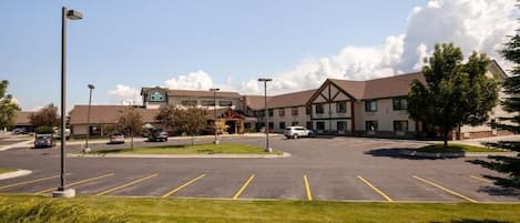 A hotel with a parking lot, a building with a sign, and a clear sky.