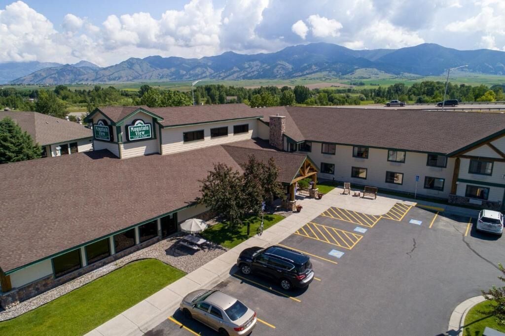 A hotel with a parking lot, Mountain View Inn sign, and a view of mountains.