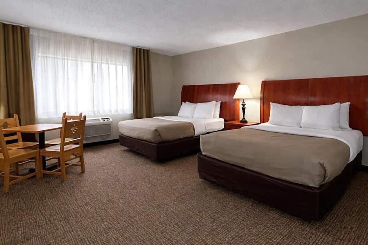 Ett hotellrum med två sängar, ett skrivbord och en stol.