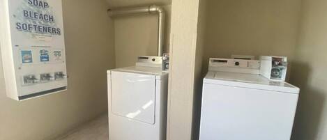 A laundry area with two washing machines and a soap, bleach, and softener dispenser.