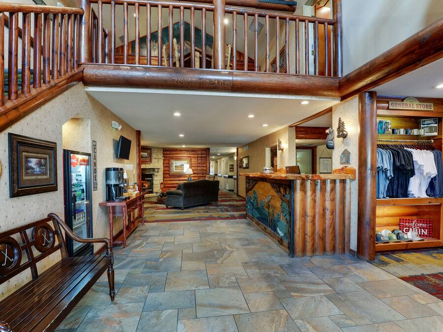 A spacious lobby with a wooden staircase, a reception desk, and a clothing store.