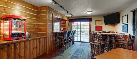 Un restaurant chaleureux avec des murs en bois, un appareil à pop-corn et une grande table entourée de chaises.