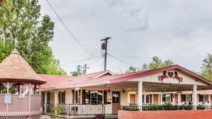 A building with a covered porch, a small gazebo, and a brick entrance.