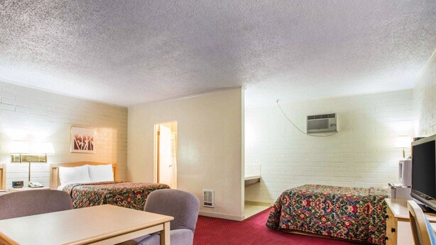 A motel room with two beds, a TV, a desk, and a chair.