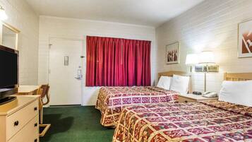 A hotel room with two beds, a TV, a dresser, and a door.