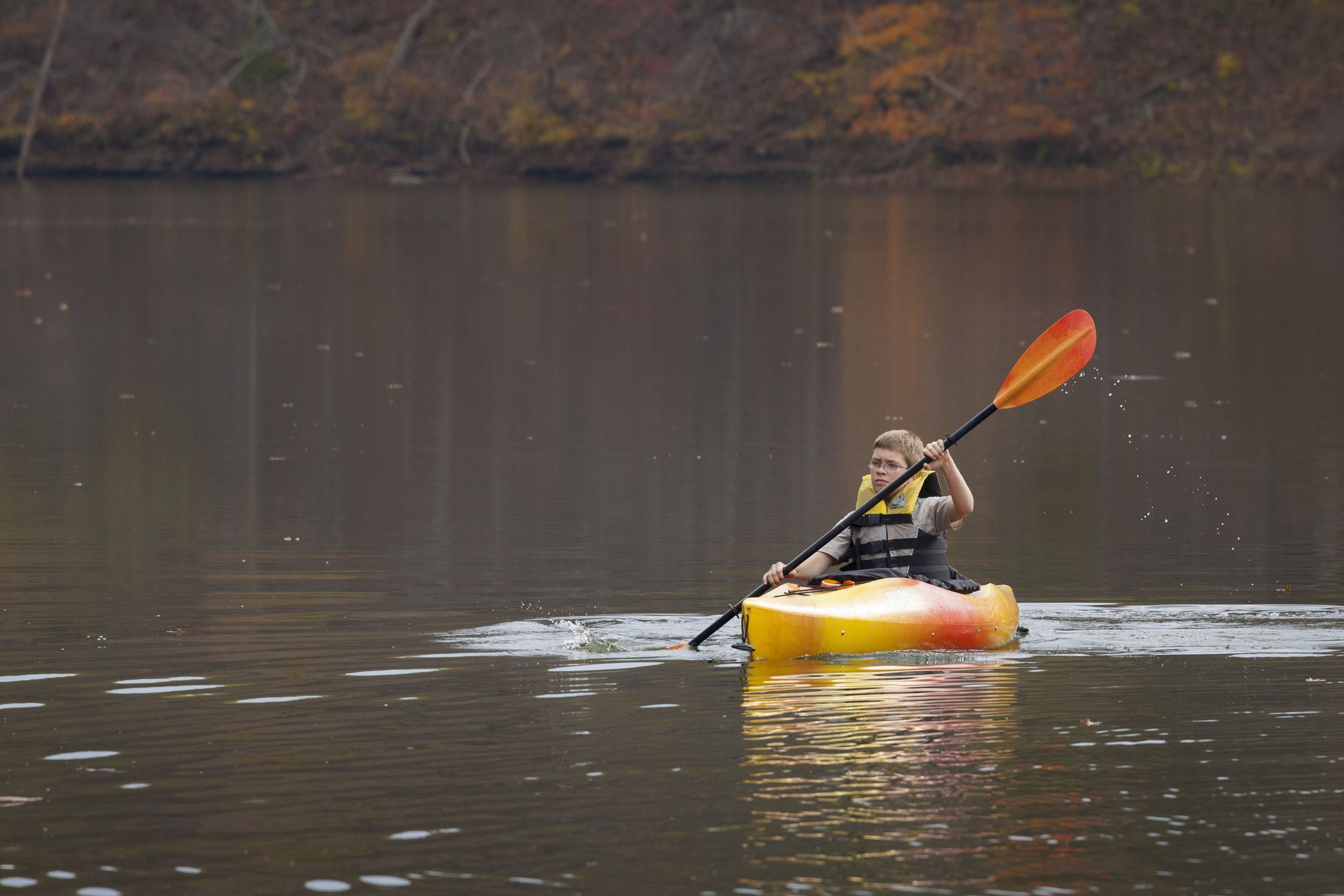 A person kayaking on a calm body of water.