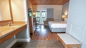 A hotel room with a bathroom, a bed, a bench, and a chair. - Carter Caves State Resort Park (Olive Hill)