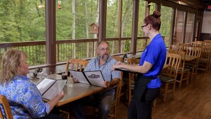 A restaurant with wooden furniture and large windows overlooking a forest. - Carter Caves State Resort Park (Olive Hill)