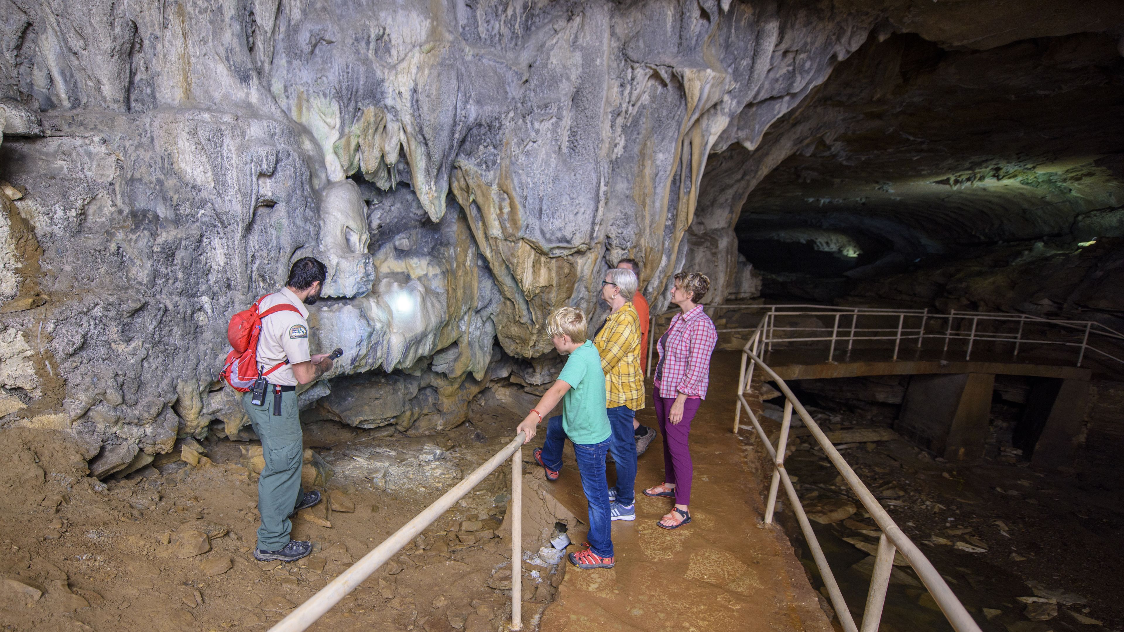 A group of people exploring a cave with a wooden walkway and rocky walls.