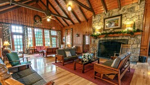 Un chalet spacieux doté d’une cheminée en pierre, de meubles en bois et de grandes fenêtres.