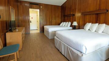 Quarto de hotel com duas camas, uma escrivaninha e uma cadeira, e paredes de madeira.