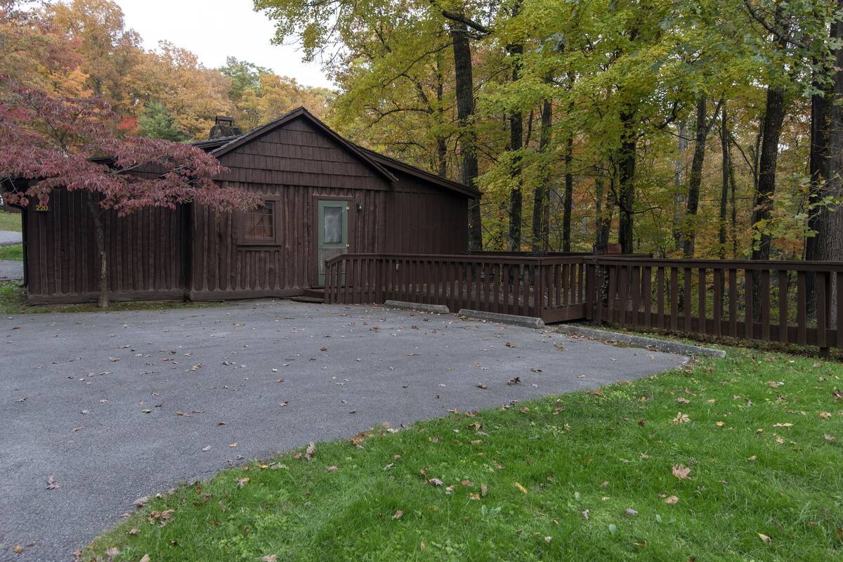 Eine Holzhütte mit Veranda, umgeben von Bäumen und einer Wiese.