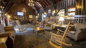 A rustic interior with wooden beams, leather sofas, rocking chairs, and a bar area. - Pine Mountain State Resort Park (Pineville)
