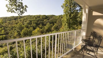 A balcony with a white railing overlooking a forested hillside.