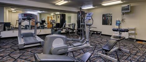Ett gym med löpband, crosstrainers och träningsbänkar för styrketräning.